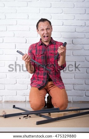 Shocked Young man confused about assembling furniture 