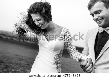 Black and white picture of gorgeous smiling brunette holding man's hand during a walk