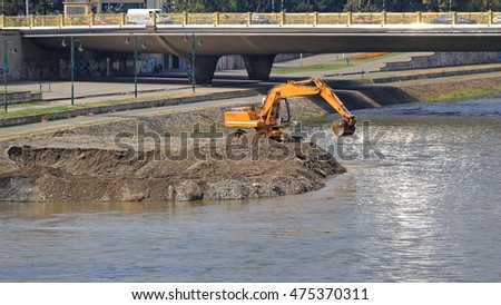 Excavator Machine Digging Levee at River Embankment Royalty-Free Stock Photo #475370311