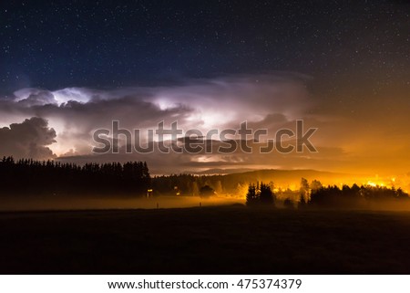 Beautiful view of dramatic dark stormy sky and lightning over small village at night. Germany, Bavaria.