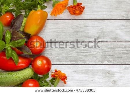 Vegetables, parsley and basil, flowers on wooden background.