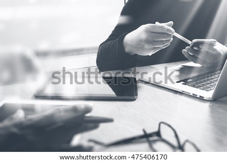 Photo website graphic designer hand meeting team with new project modern studio laptop digital tablet smart phone on marble table.Books papers documents, sun flare effect, black white
