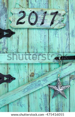 Year 2017 in black iron numbers and metal star hanging on antique rustic mint green wood door; Happy New Year concept 