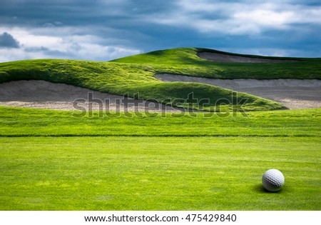 Green grass background on golf course with bunker and golf ball at fairway. Sand trap or hazard on the lawn for playing in golf. Sport-club for leisure and playing with a ball on open air.
