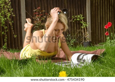 Young woman lying in garden reading magazine