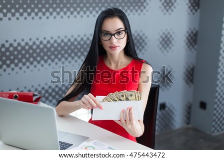 Young business woman holding money in envelope in the office