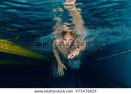 Young swimmer swimming in a pool underwater
