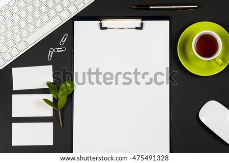 Office black desk table with white computer, business card blank, flower, coffee cup and pen. Top view with copy space. Corporate stationery branding mock-up