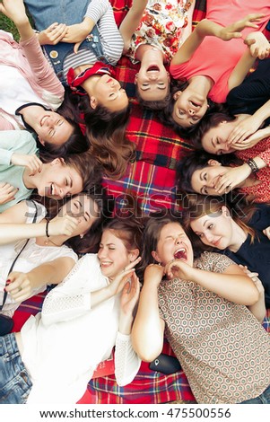 happy group of women faces in circle laughing and having fun on picnic top view, lying on blanket, joyful moments celebration in summer park
