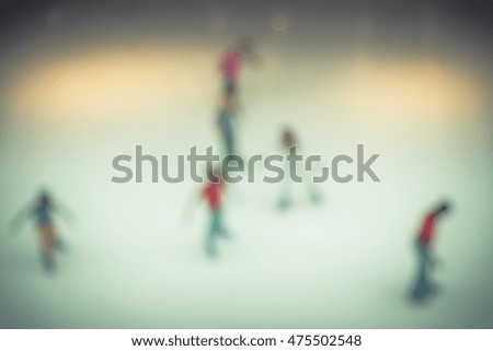 Top view blurred motion background of parents and kids play indoor ice skating in modern shopping mall. Defocused of indoor ice skating with people on the ice rink. Natural light from glass roof.