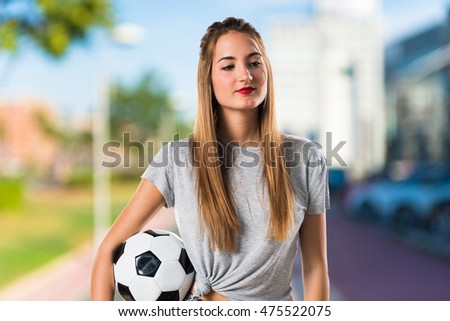 Woman player holding a soccer ball on unfocused background