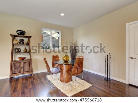 Dining room with round glass table and contemporary wooden chairs. Decorated with dry branches in a vase. Northwest, USA