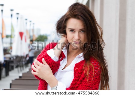 Business woman in a red cardigan and white shirt on a background of a sidewalk cafe