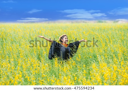 Stock image of happy female graduate, outdoor setting relaxed, smiling teenage on a grass field