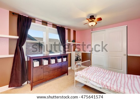 Minimalistic design of kid's bedroom  interior with pink accent walls. Iron bed, white closet and carpet floor. Northwest, USA
