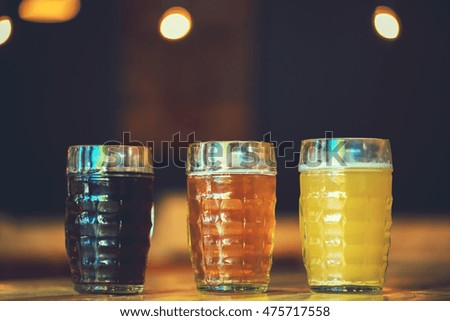 Beautiful background of the Oktoberfest. Glasses of cold fresh white, light and dark beer on the wooden bar counter in the pub. Assorted alcohol in a Flight Ready for Tasting