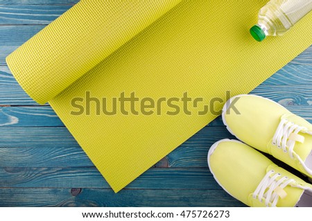 Healthy lifestyle background. Yoga mat, sport shoes, bottle of water on wooden background. Concept healthy and sport life. Top view Royalty-Free Stock Photo #475726273