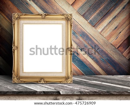 Gold victorian picture frame on plank wooden table top at tropical diagonal wood wall,Template mock up for adding your design and leave space beside frame for adding more content.