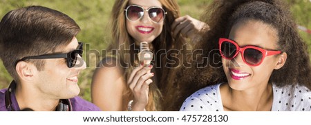 Young people with sunglasses sitting together on a ground with ice cream