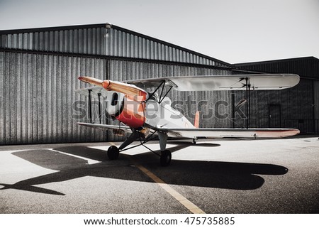 Vintage old plane in front of the hangar. Shadow on the ground.