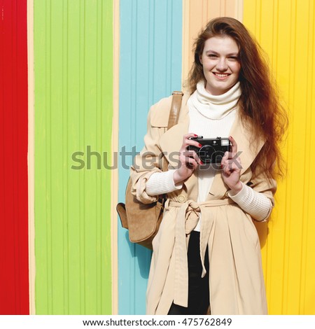 Young stylish hipster girl tourist walking on the street, autumn fall fashion style. Lifestyle portrait of pretty young woman having fun in the city. Photographer making pictures