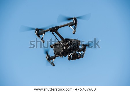 Drone-quadrocopter with camera hovers on the blue sky/Drone flying in the sky