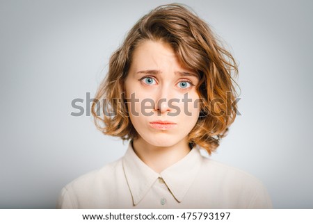 beautiful young woman is offended, close-up, isolated on a gray background
