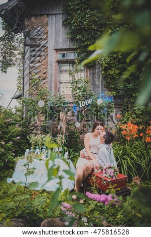 beautiful young couple stands near the old wooden house. Funny pictures. The house overgrown with ivy. Decorated photosesion.