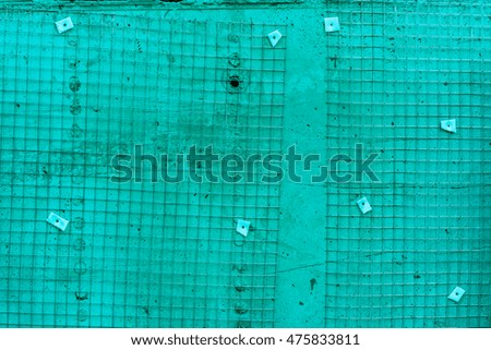 White blue wire metal fence toned to color, small parts of netting with shadows against wall as background with screws, netting as texture against light wall