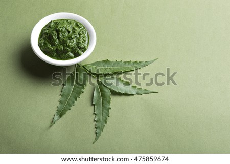 Medicinal Neem leaves with paste in bowl on green background 