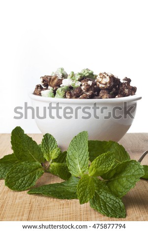A white bowl of gourmet chocolate and peppermint popcorn over wooden background.