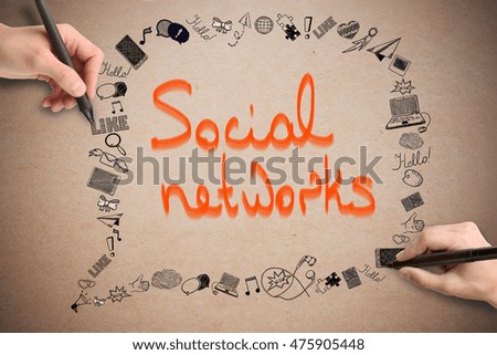 Hands drawing media related doodles on cardboard background with orange text. Social networking concept