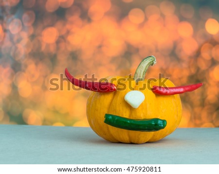 pumpkin on orange background, red chili in pumpkin, yellow pumpkin make mouth by green chili, garlic on yellow pumpkin,