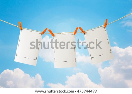 Photo cards and clip hanging on the clothesline on sky background