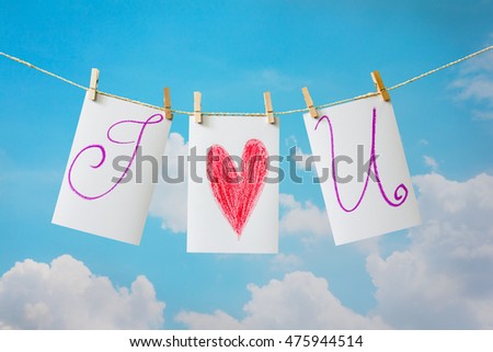 Photo cards with  hand write text "I LOVE U " and clip hanging on the clothesline on sky background