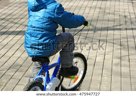 The image of the child who is riding a children's Bicycle. Rear view.