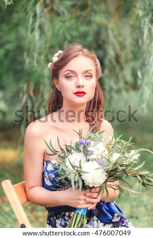 beautiful young woman with a bouquet of flowers in their hands looking right outdoor