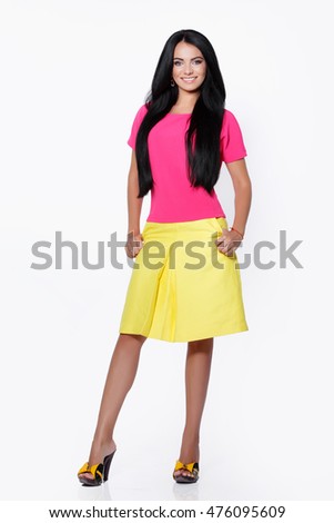 Fashion studio photo of happy smiling young woman isolated on white background. Cheerful brunette girl with long straight hair. Attractive caucasian model  in pink blouse and yellow skirt