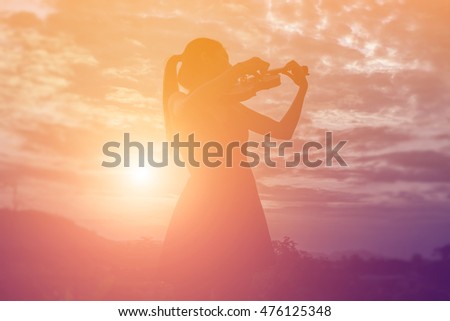 Young woman playing the violin With mountains in the background
