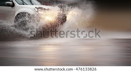 Splash by a car through flood water after hard rain,blurry movement and selective focus. Royalty-Free Stock Photo #476133826