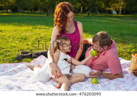 Happy young family having picnic at meadow at summer day.