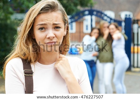 Unhappy Girl Being Gossiped About By School Friends Royalty-Free Stock Photo #476227507