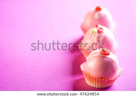 Delicious pink cupcakes on purple background. Shallow depth of field.