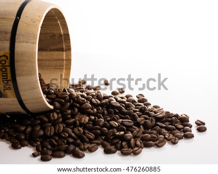 wooden barrel from which grains of coffee go out on white background with space to the right to insert text