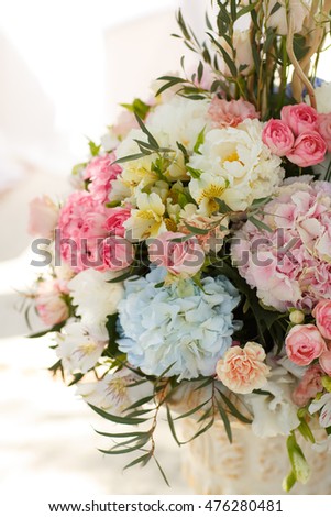 Luxury wedding decorations of fresh flowers outdoors. Beautiful marriage day decor rustic style in pink, blue and white colors. Bridal ceremony decoration indoor. Selective focus and soft grain filter