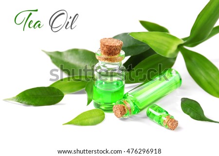 Bottles with tea tree essence and green leaves on white background. Space for text.