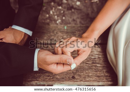 Hands newlyweds with wedding rings on background wooden texture
