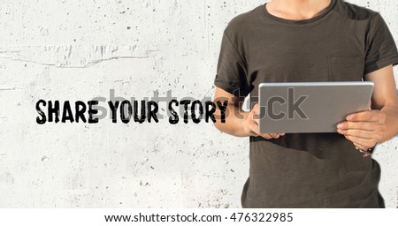 Young man using tablet pc and SHARE YOUR STORY concept on wall background