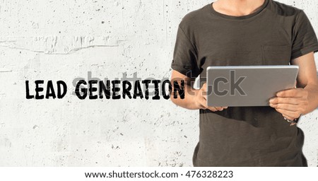 Young man using tablet pc and LEAD GENERATION concept on wall background