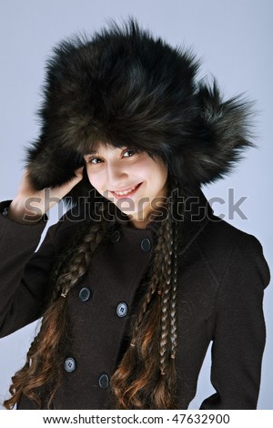 Portrait of the fabulously beautiful girl in big fur cap on a dark background